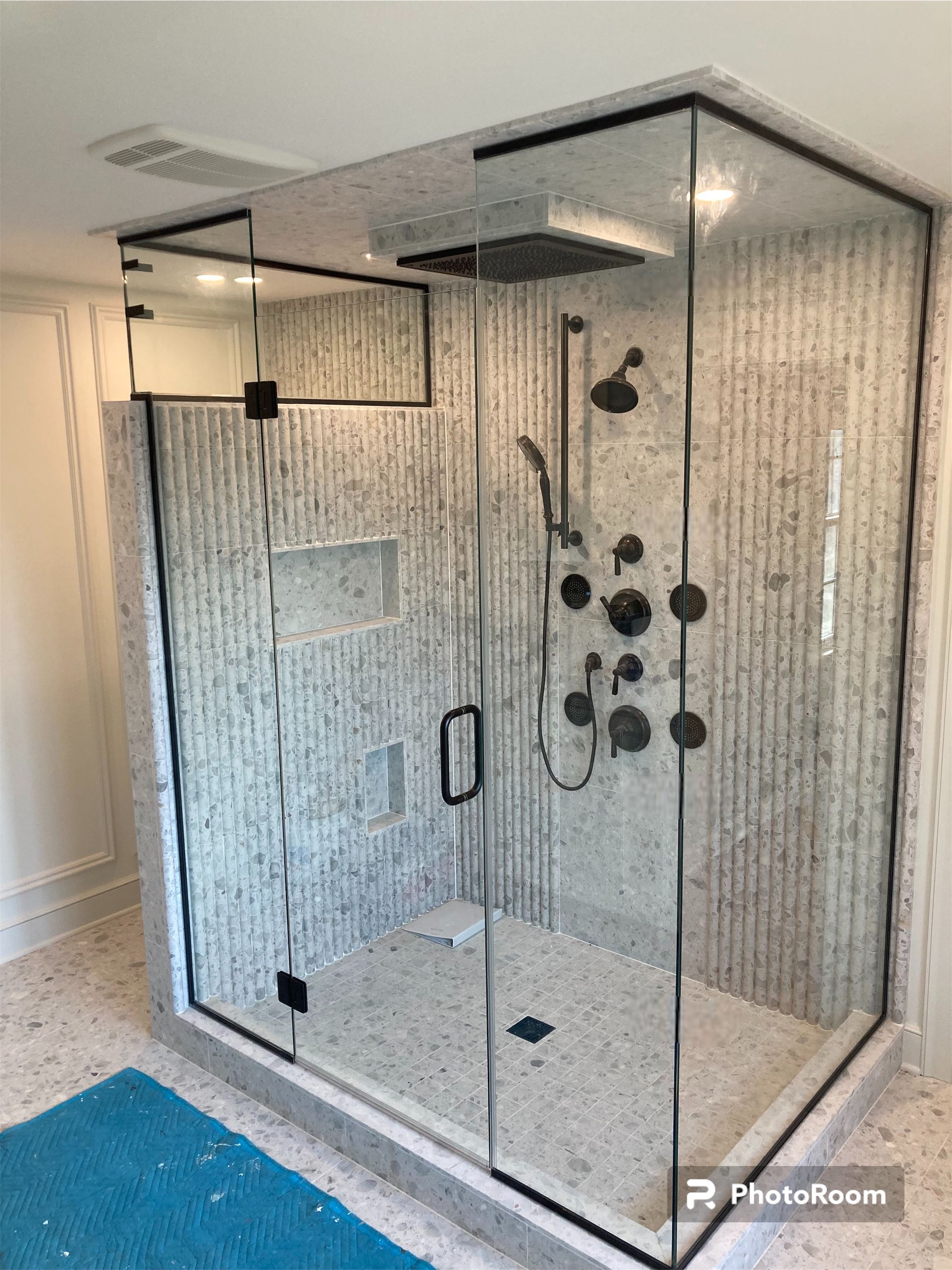 A bathroom with a walk in shower with a glass door.