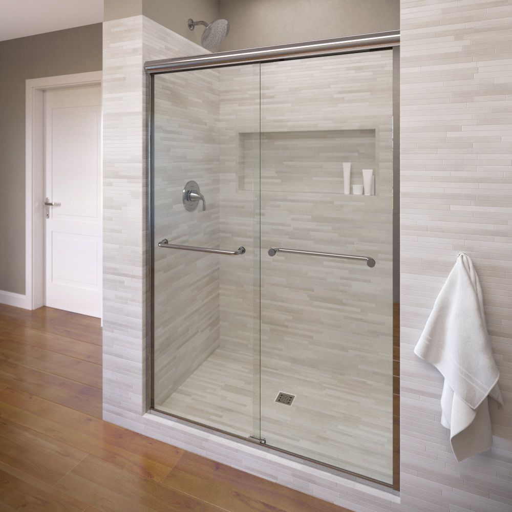 Shower with sliding glass doors, chrome hardware, recessed shelf, tiled walls, and towel.