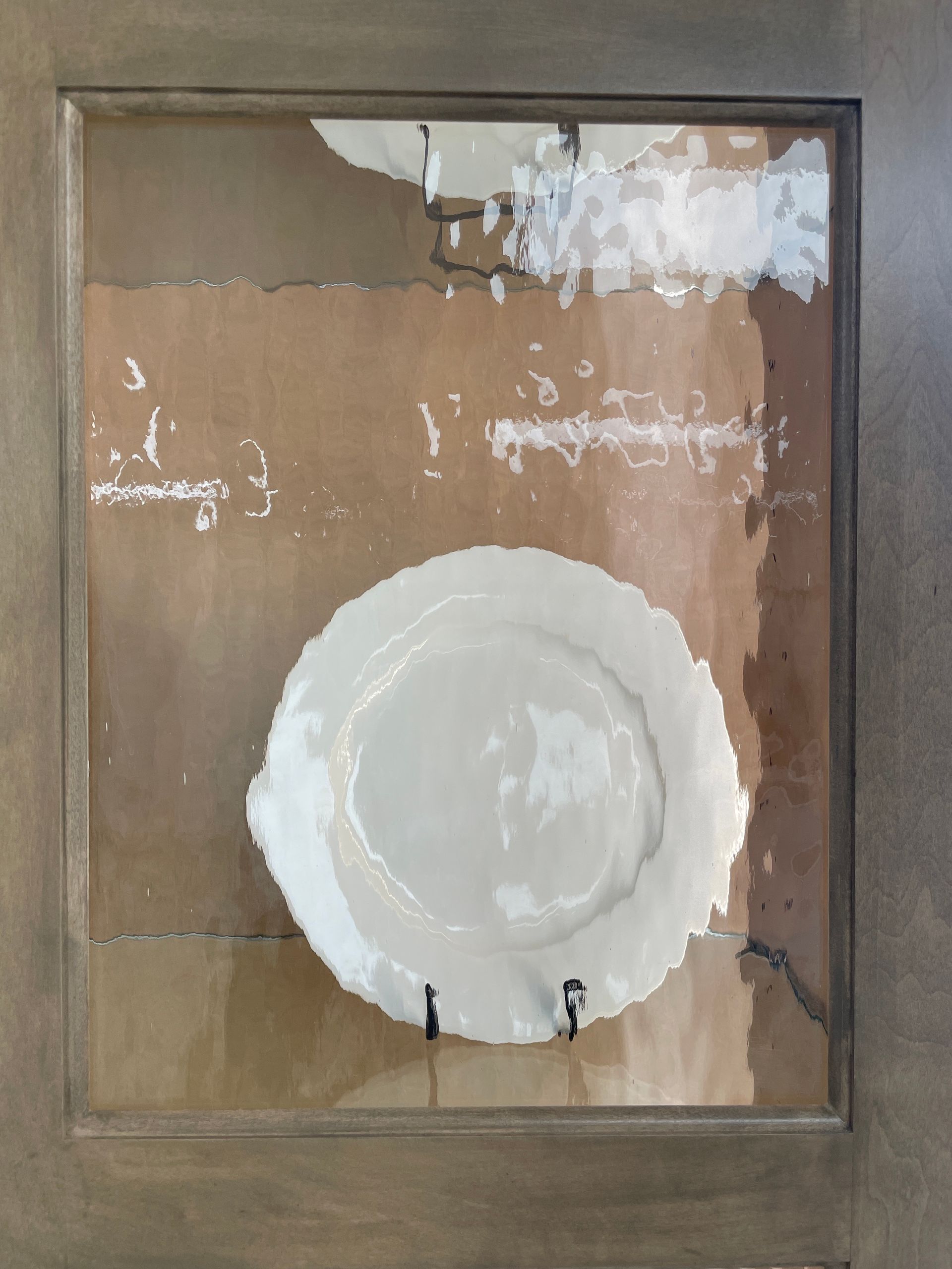 White plate mounted in a frame against a textured tan background.