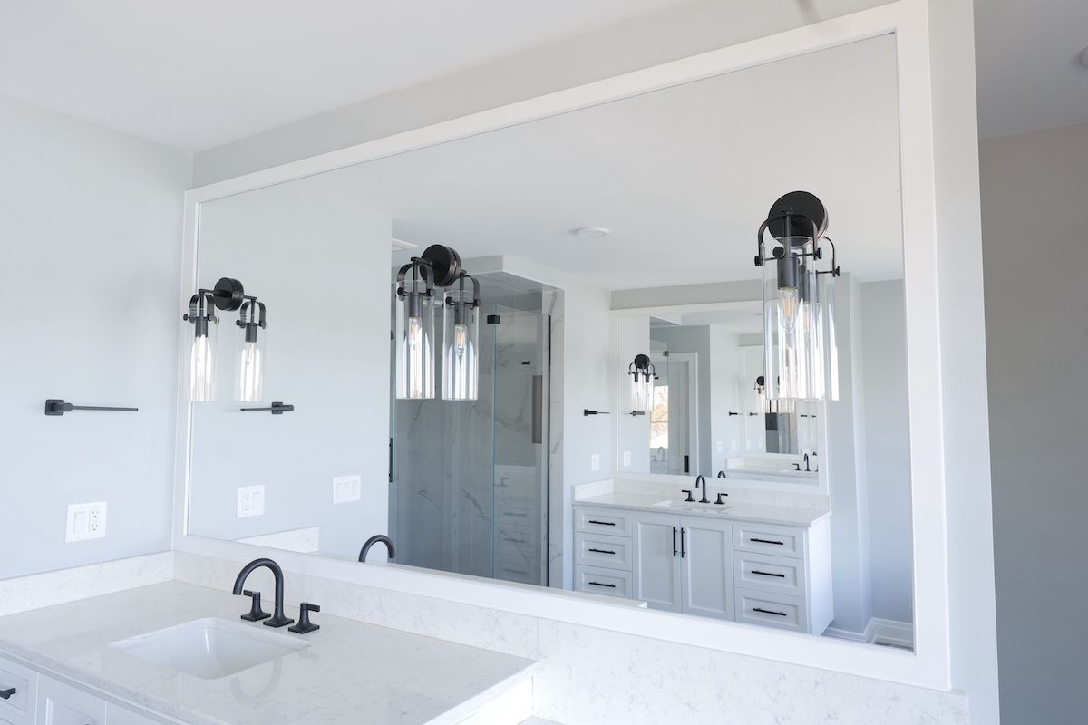 Bathroom with large mirror, two sconces, white vanity, and marble countertops.