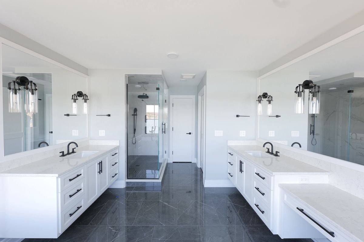 Modern white bathroom with two vanities, a glass shower, and gray tile floor.