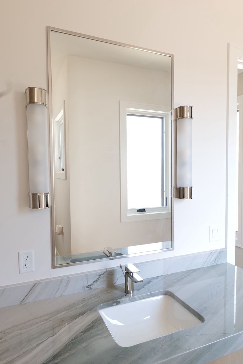 Bathroom vanity with mirror, sconces, and marble countertop.