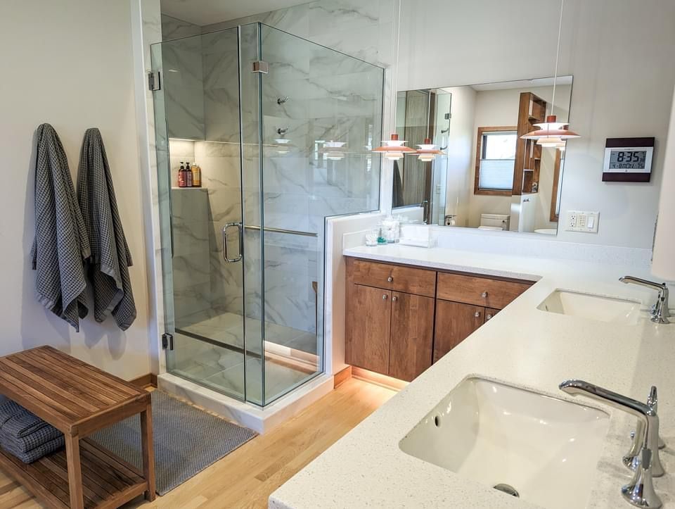 Modern bathroom with glass shower, double sinks, and wooden vanity.