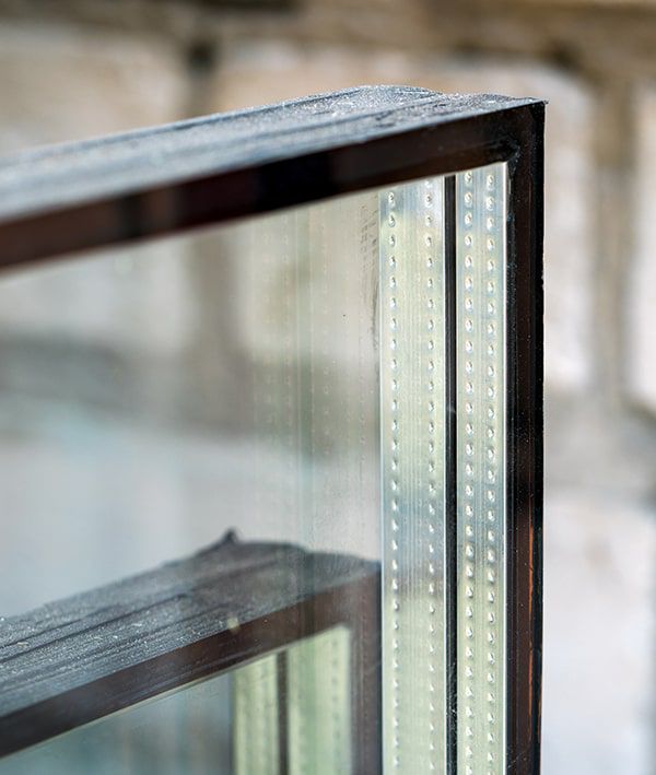 Close-up of a window pane showing a black frame and multiple small, evenly spaced dots on the glass edge.