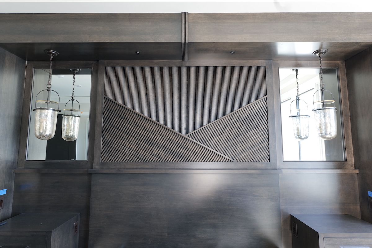 Dark wood built-in wall with central textured panel and two mirrored sections, each with a hanging lantern.