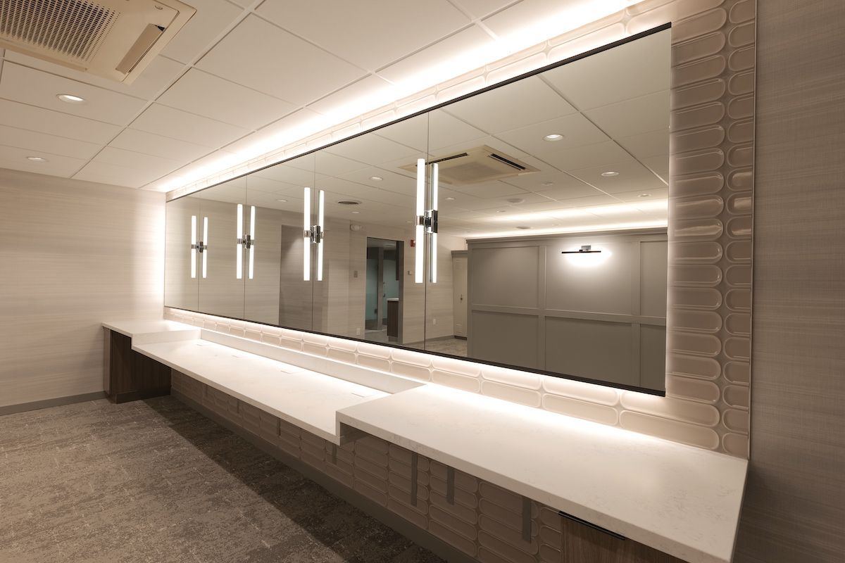 Modern restroom with long counter, large mirror, and decorative lighting.