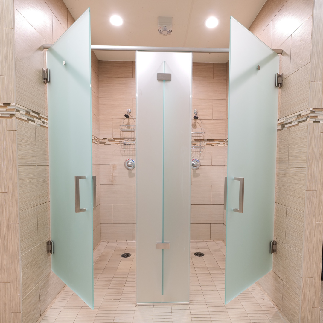 Three frosted glass shower stalls in a bathroom with beige tile walls and floors.