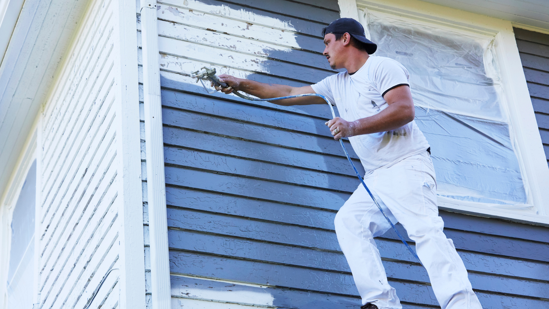 a man is painting a wall with a paint roller and bucket .