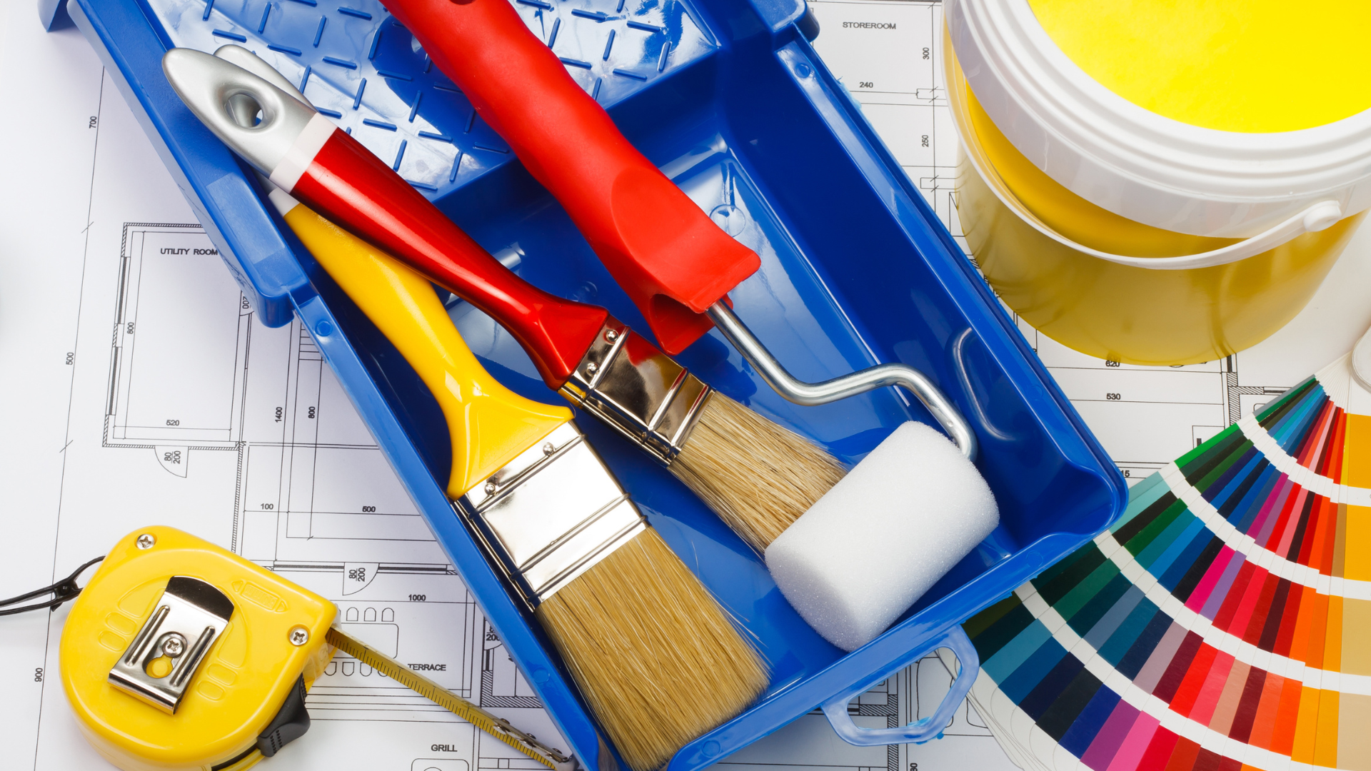 a man is painting a wall with a paint roller and bucket .