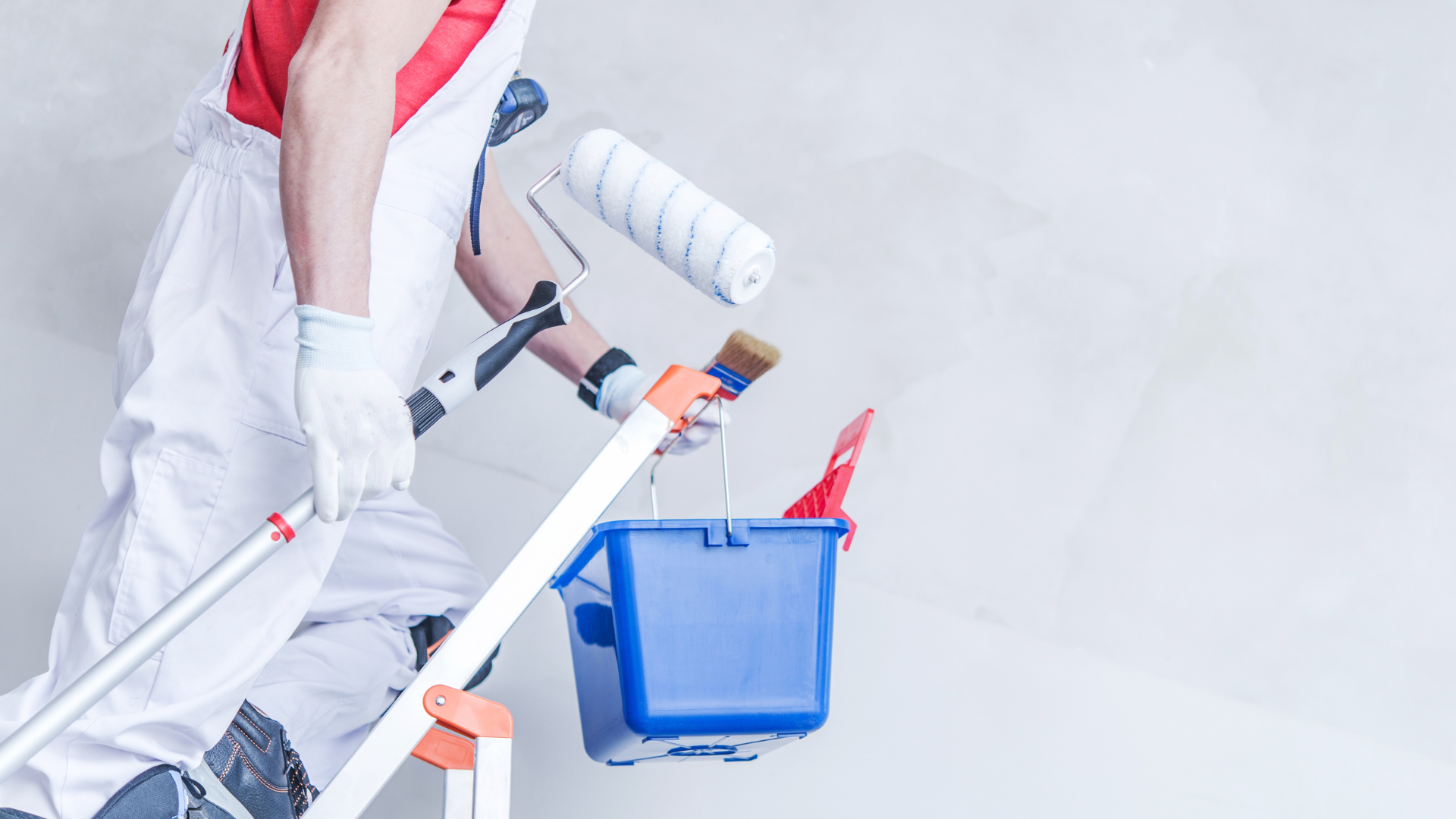 a man is painting a wall with a paint roller and bucket .