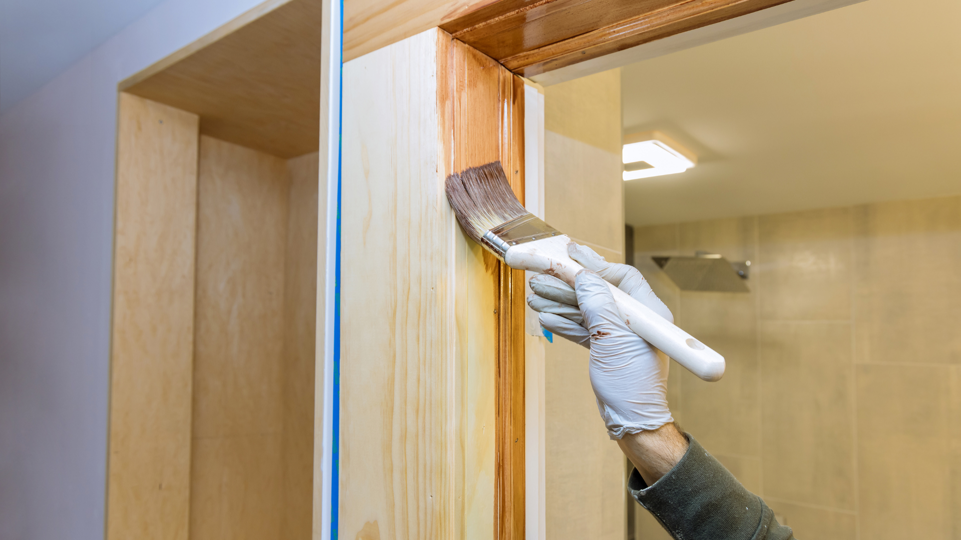 a man is painting a wall with a paint roller and bucket .