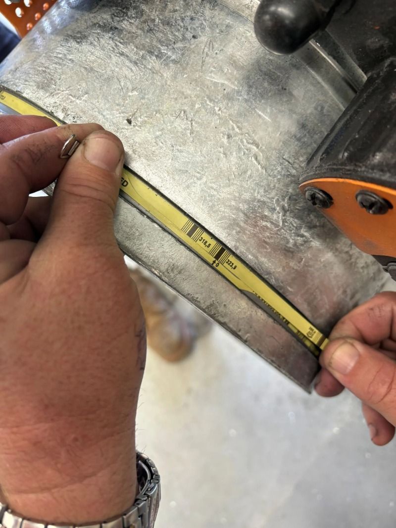 Hands measuring a yellow tape on a circular saw blade with a metal ruler nearby