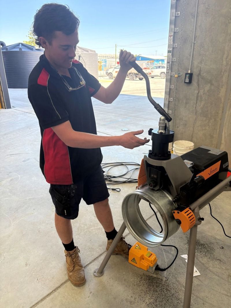 Worker adjusting a large work light indoors, with a corded tool and concrete wall nearby