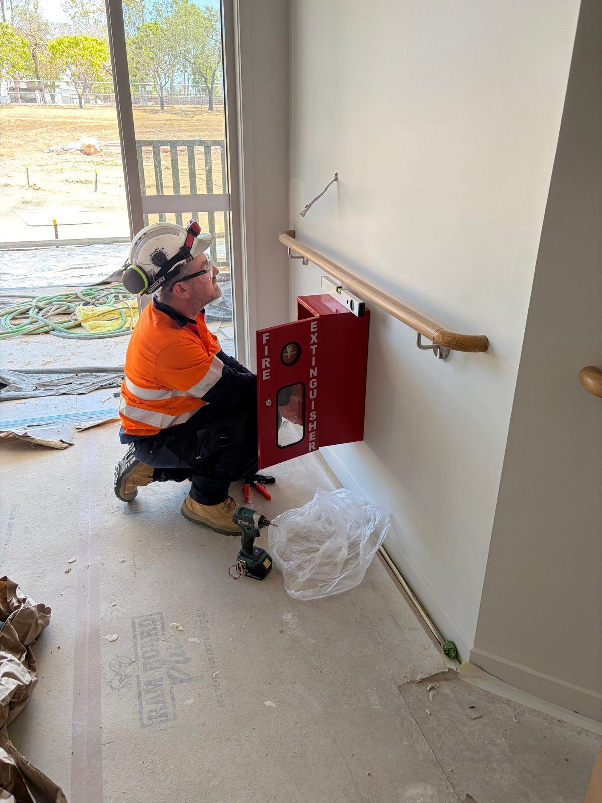 RPS Fire technician installing a fire extinguisher cabinet and signage at an aged care facility in M