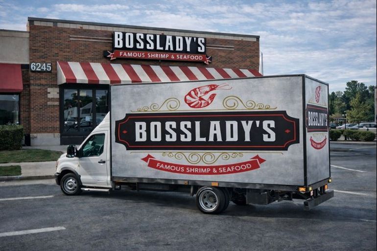 A Bosslady's Famous Shrimp & Seafood delivery truck parked in front of their brick restaurant storefront.