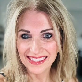 A woman with blonde hair and blue eyes is smiling for the camera.
