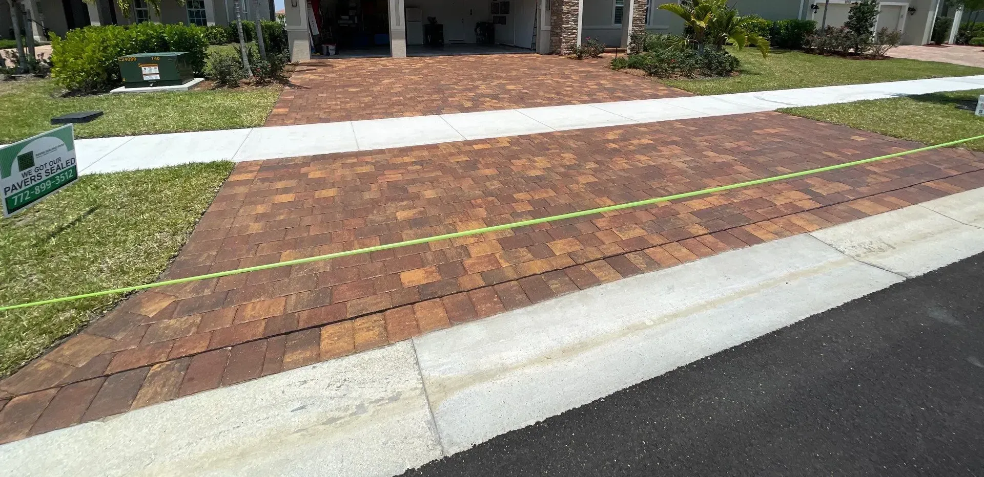 Driveway and sidewalk with a measured brick-paver area marked by yellow tape.