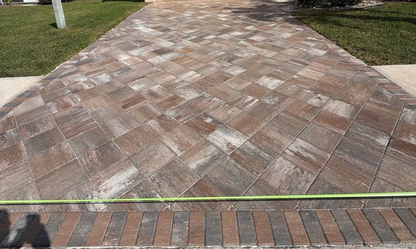 Brick and stone paver driveway with a herringbone pattern and grassy edges