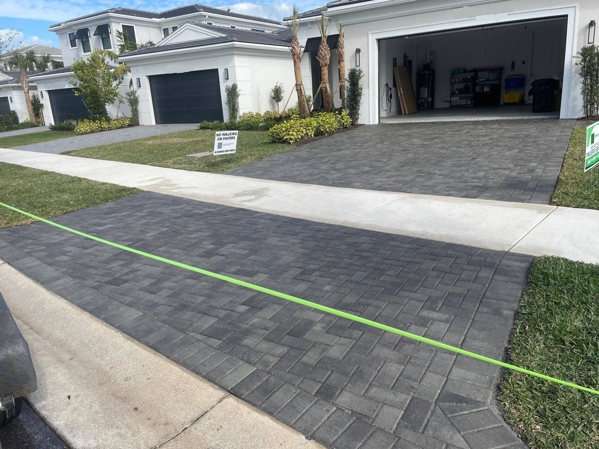 New paver driveway in front of a white house with open garage