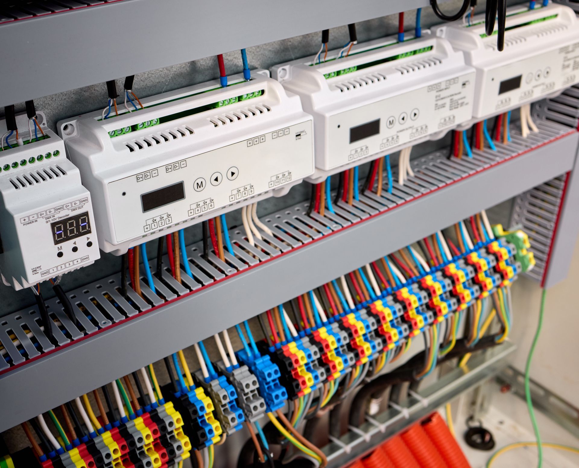 Electrical control panel with white modules, colorful wiring, and terminal blocks in an equipment cabinet