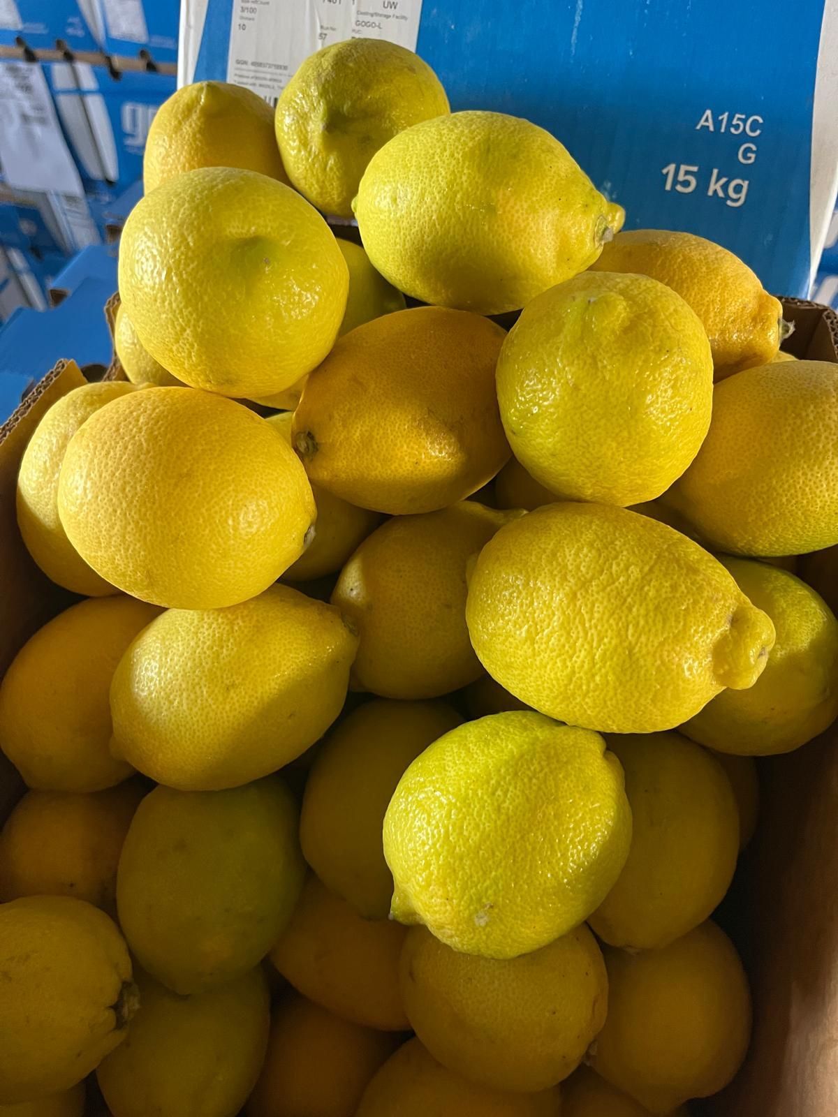 Un mucchio di limoni gialli in una cassa blu contrassegnata con la scritta