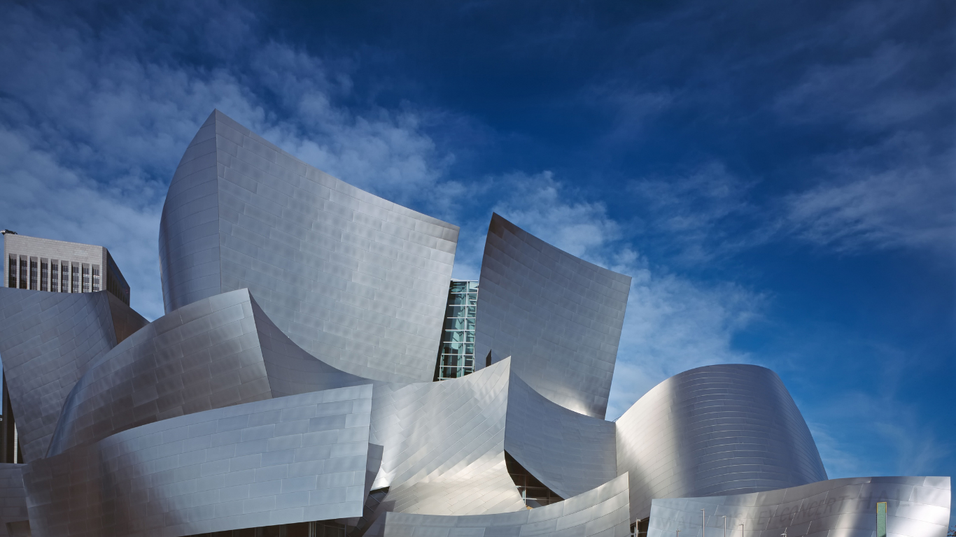 Walt Disney Concert Hall in Los Angeles, featuring iconic curved, stainless steel panels against a deep blue sky.
