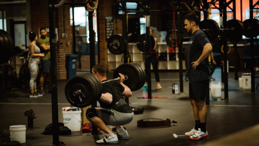 Person deadlifting a barbell in a gym in Reno, NV while others watch nearby.