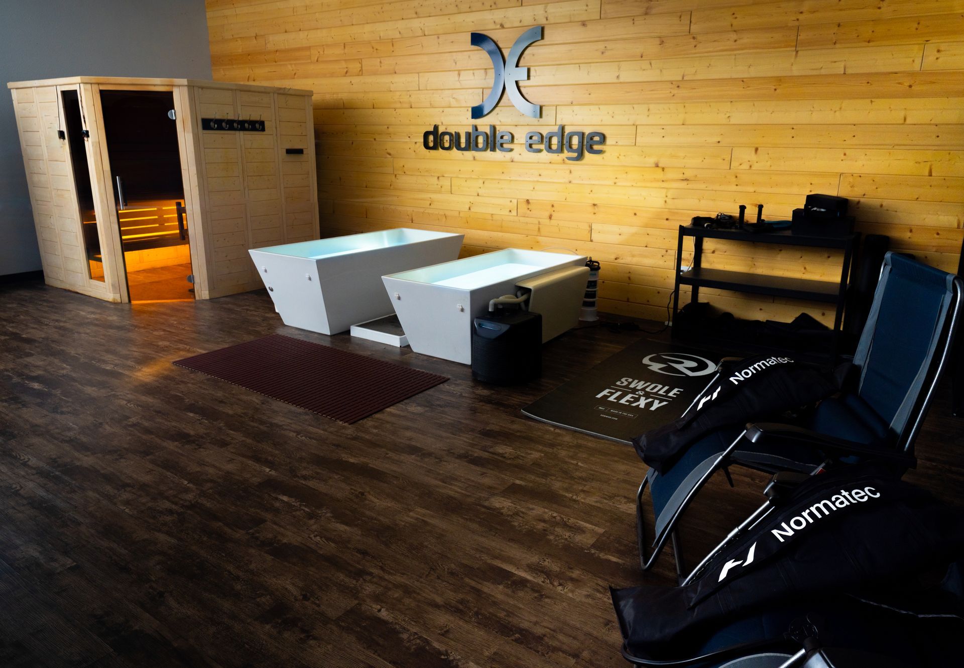 Empty modern lobby with wood floor, reception desk, logo wall, and chairs along the side