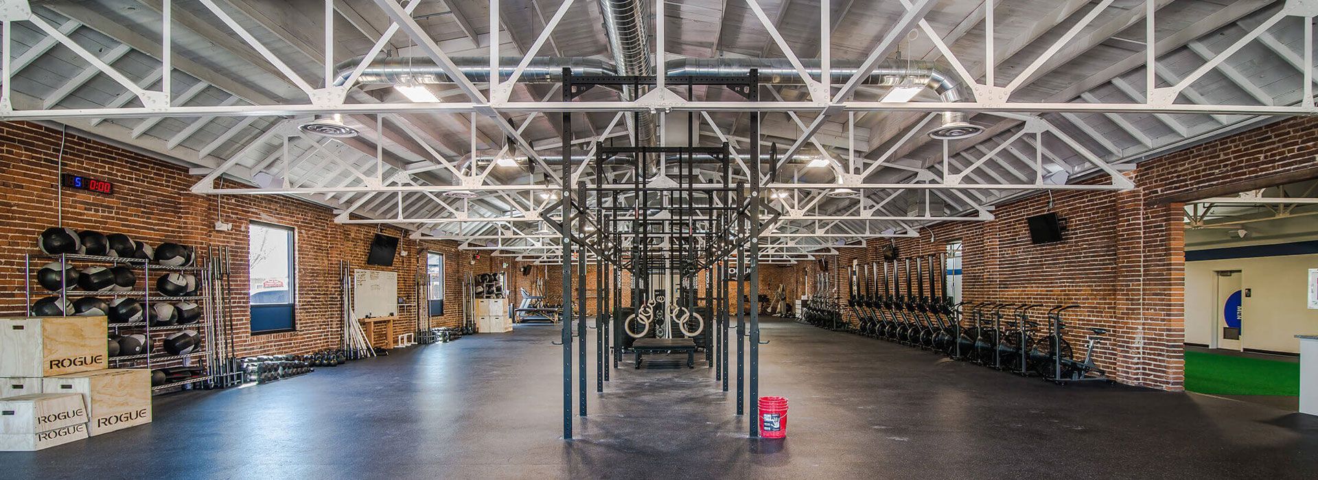 Large industrial warehouse interior with exposed beams, shelving, and a central support column on a polished floor