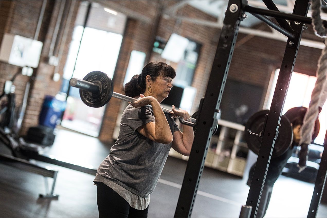 Person lifting a barbell in a gym in Reno, NV, standing beside a squat rack.