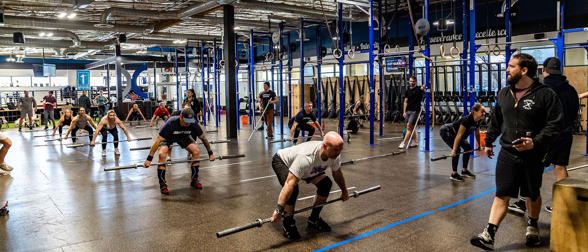 People doing group fitness exercises in a large gym in Reno, NV with black pull-up rigs and rowing machines