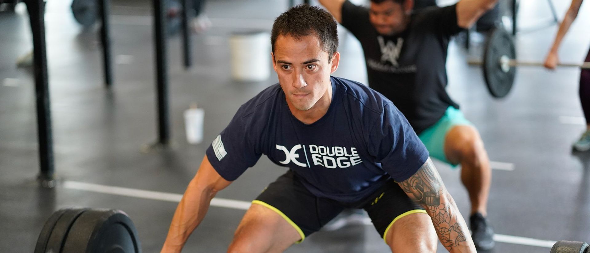 Athlete in a gym setting performs a deadlift with a barbell, focused and leaning forward.