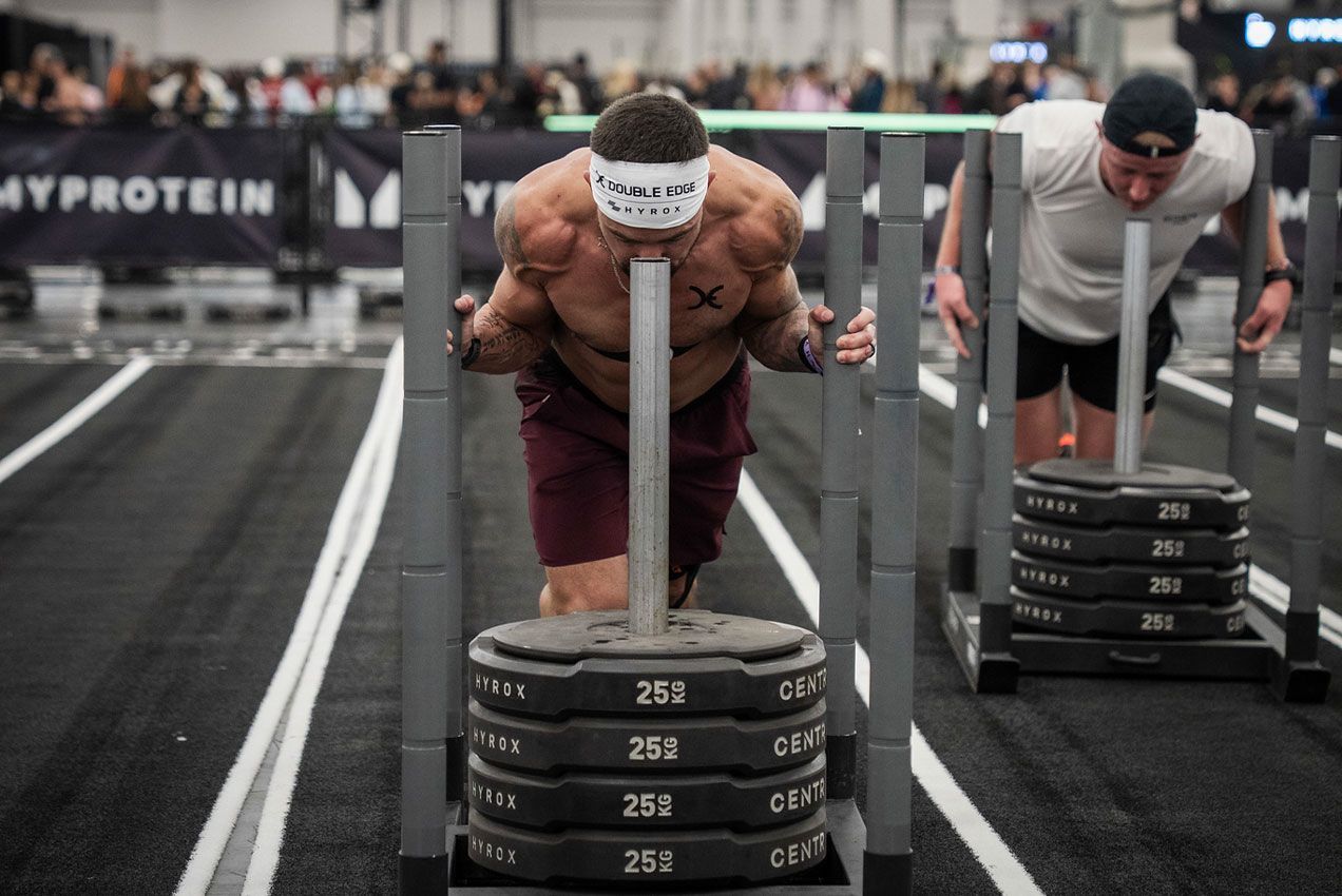 Two athletes pushing weighted sleds in a gym competition lane in Reno, NV