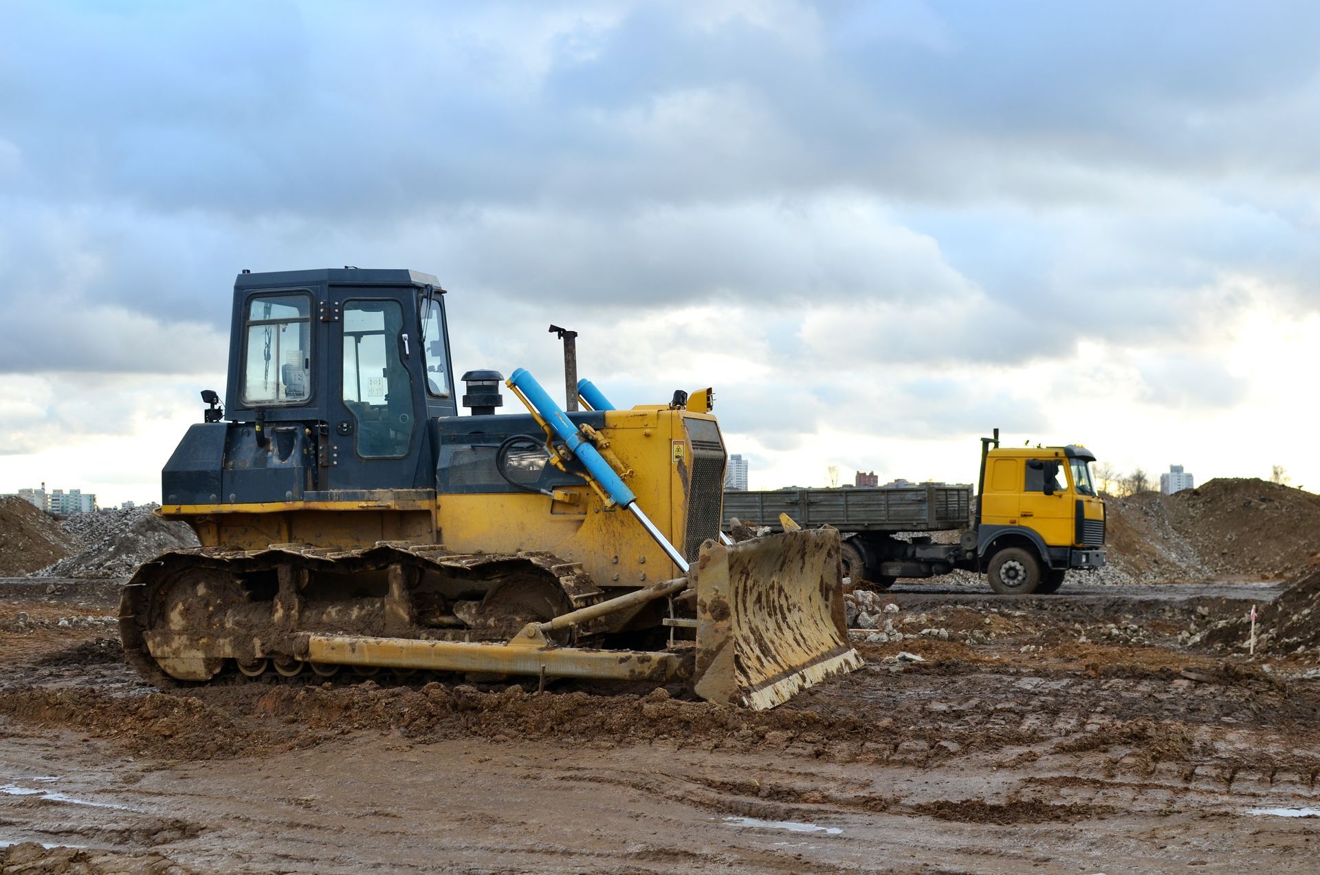 Bulldozer and dump truck operating on muddy construction site.