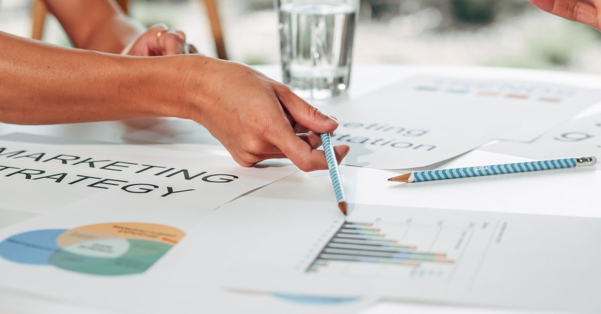 Manos señalando gráficos y diagramas impresos durante una reunión de negocios