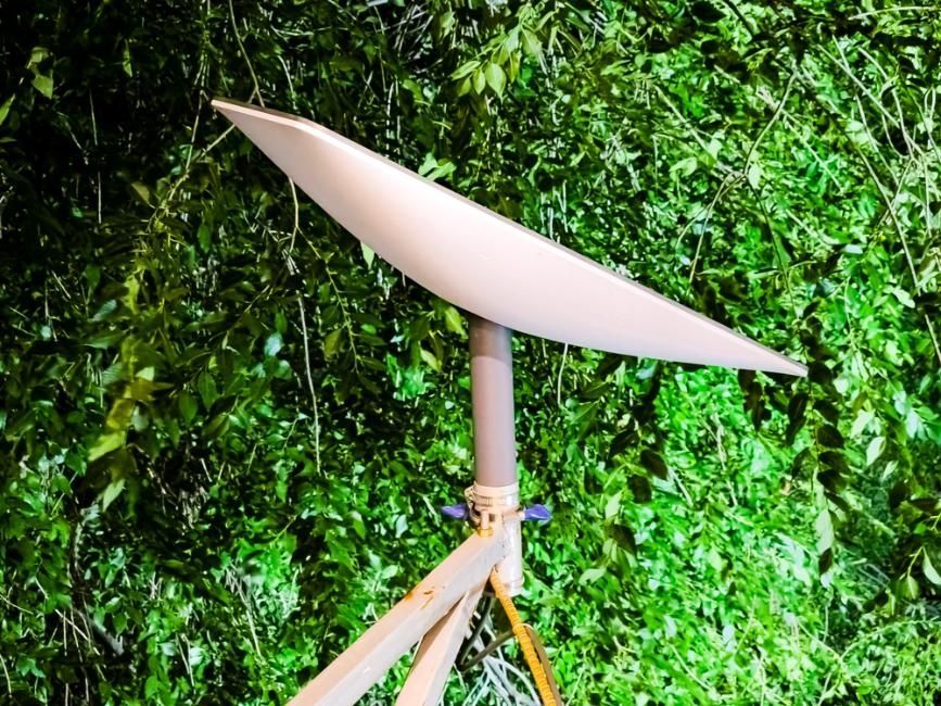 A Satellite Dish Is Sitting In Front Of A Green Wall — Highfields Antennas In Cabarlah, QLD