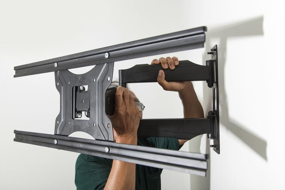 A Man Is Installing A Tv Mount On A Wall — Highfields Antennas In Clifton, QLD