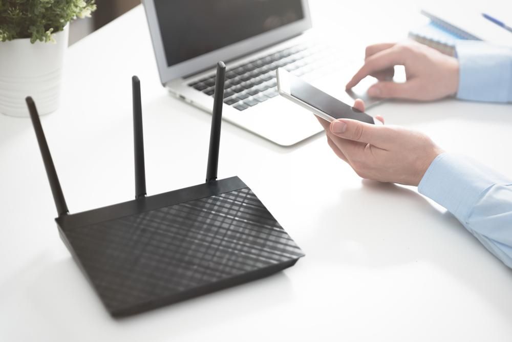 A Person Is Using A Cell Phone Next To A Router — Highfields Antennas In Esk, QLD