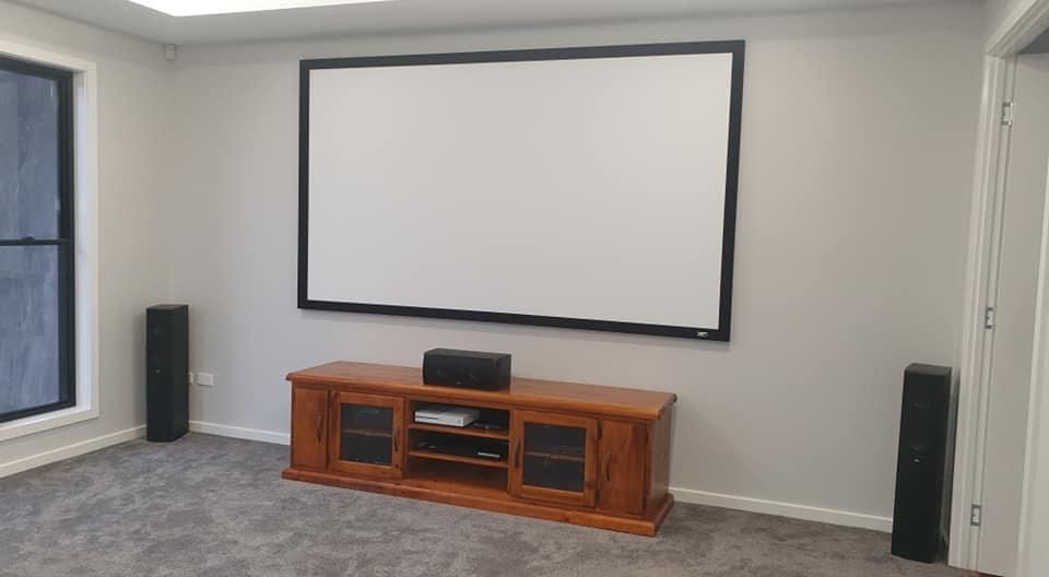 A Living Room With A Projector Screen And A Wooden Entertainment Center — Highfields Antennas In Oakey, QLD