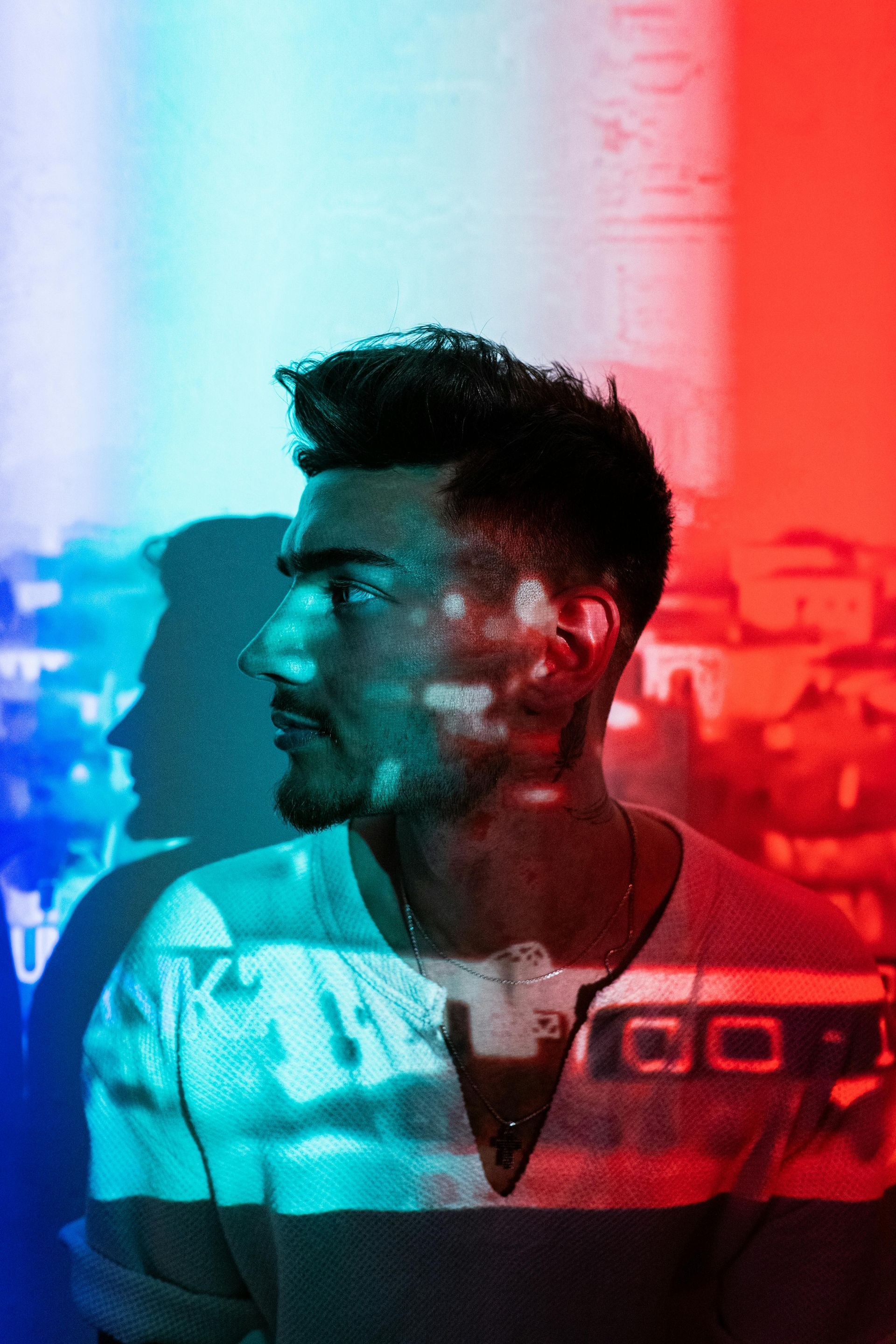 Side-profile portrait with neon red and blue split lighting on a dark background