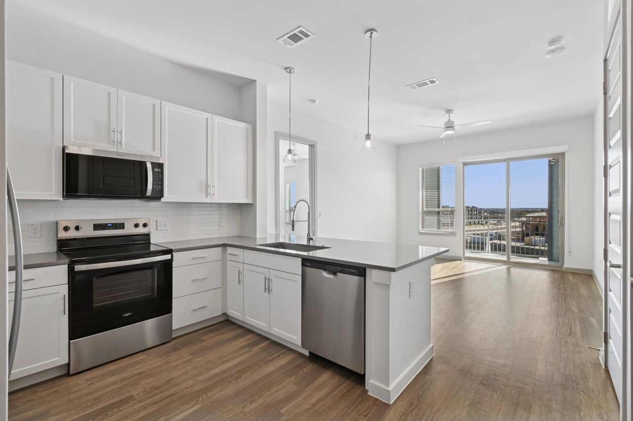 Modern kitchen with white cabinets, stainless steel appliances, and an island at Ennova Fulshear in Fulshear, TX.