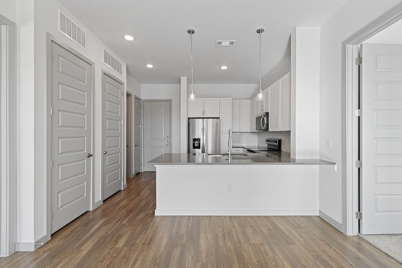 Modern apartment kitchen with island and stainless steel appliances  at Ennova Fulshear in Fulshear, TX.