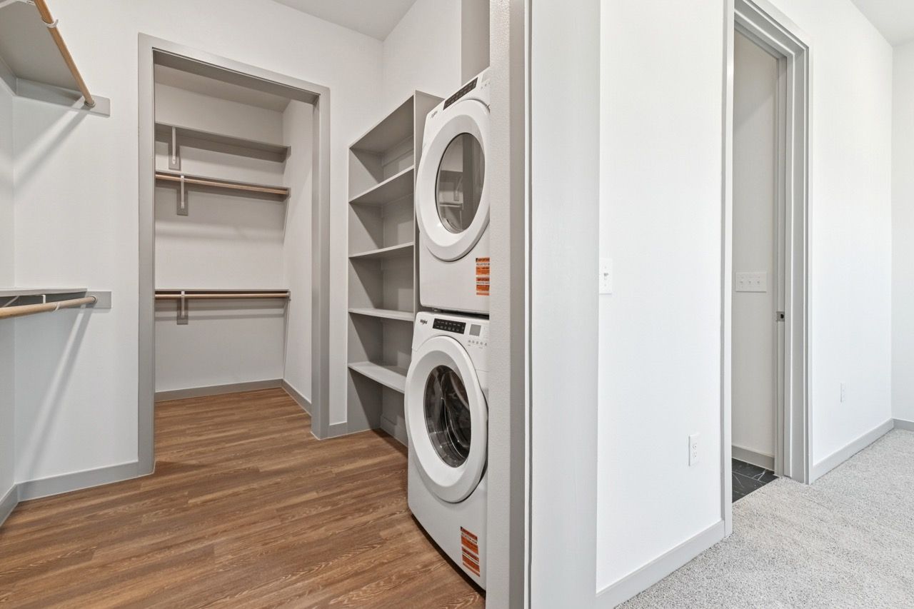 Laundry closet with stacked washer and dryer and built-in shelves  at Ennova Fulshear in Fulshear, TX.