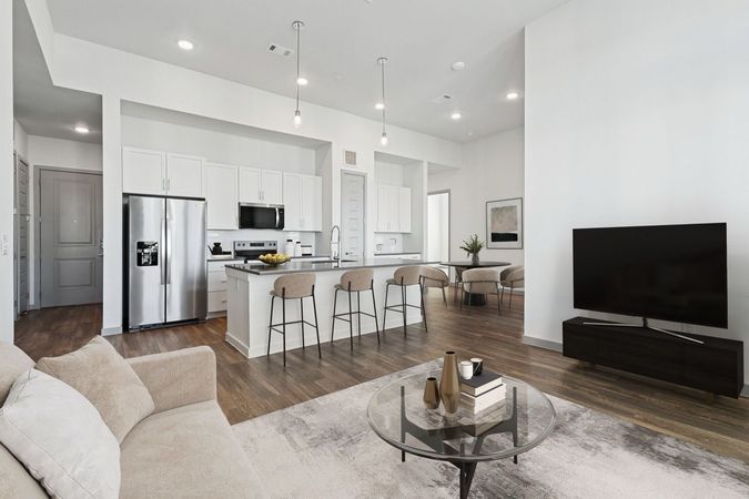 Modern open-concept living space with floors, neutral tones at  Ennova Fulshear in Fulshear, TX.