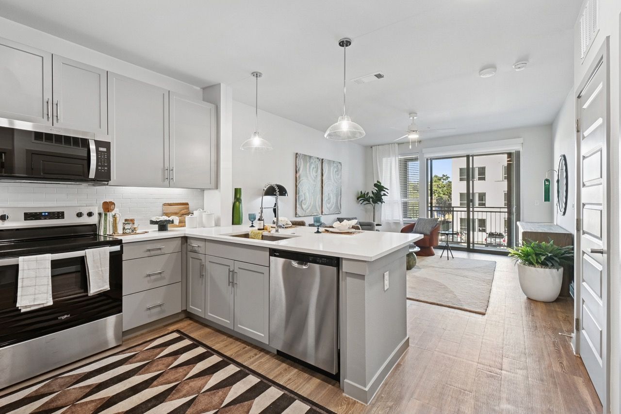 Open-concept kitchen with stainless steel appliances and an island  at Ennova Fulshear in Fulshear, TX.