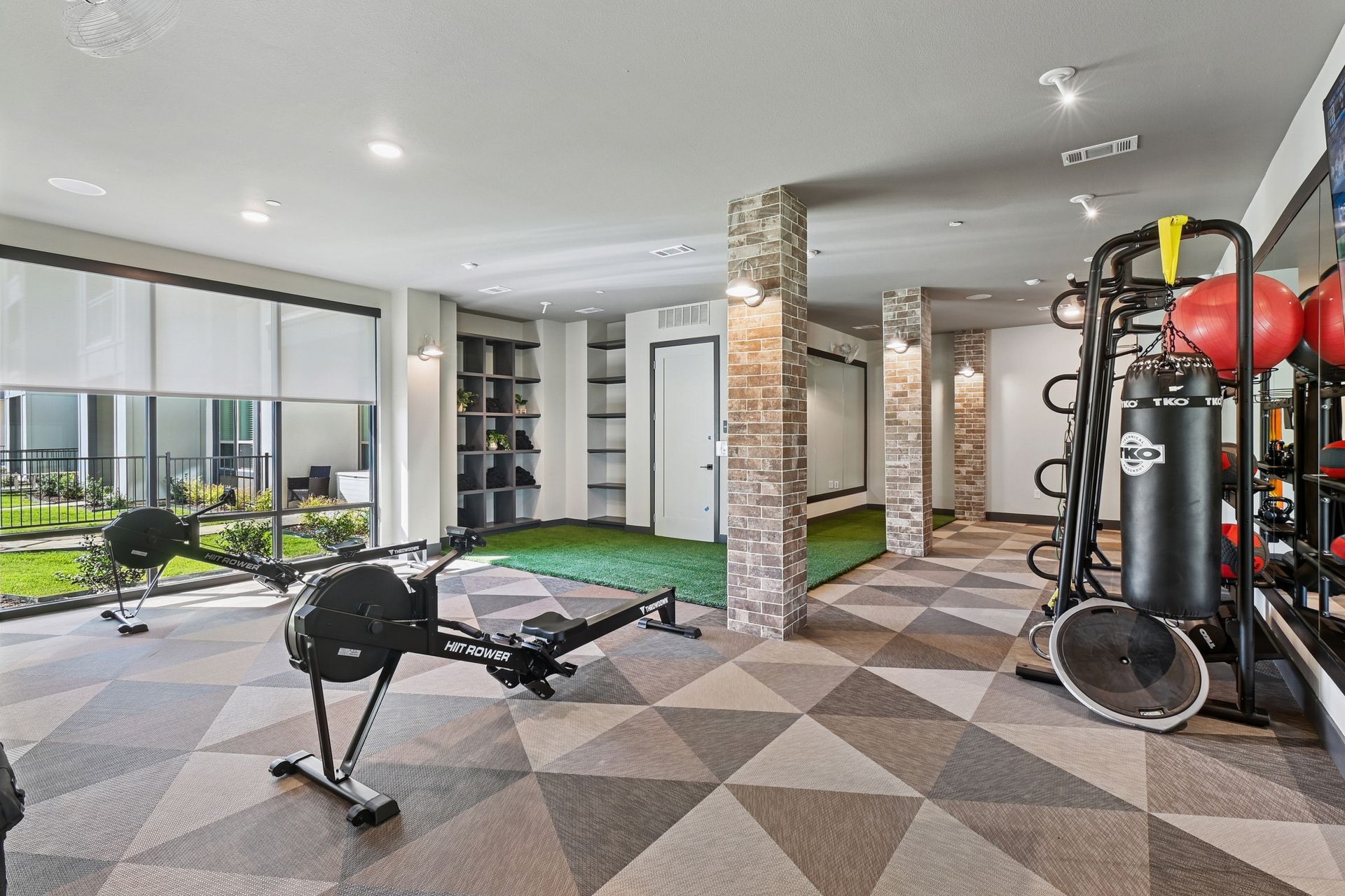 Gym interior with exercise equipment, including a rowing machine, weight rack, and punching bag.