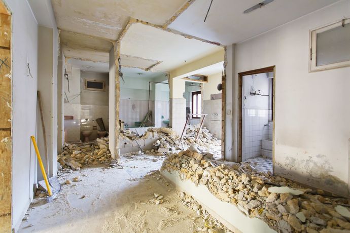 Intérieur d'un bâtiment en cours de démolition, avec des gravats au sol et des murs apparents.