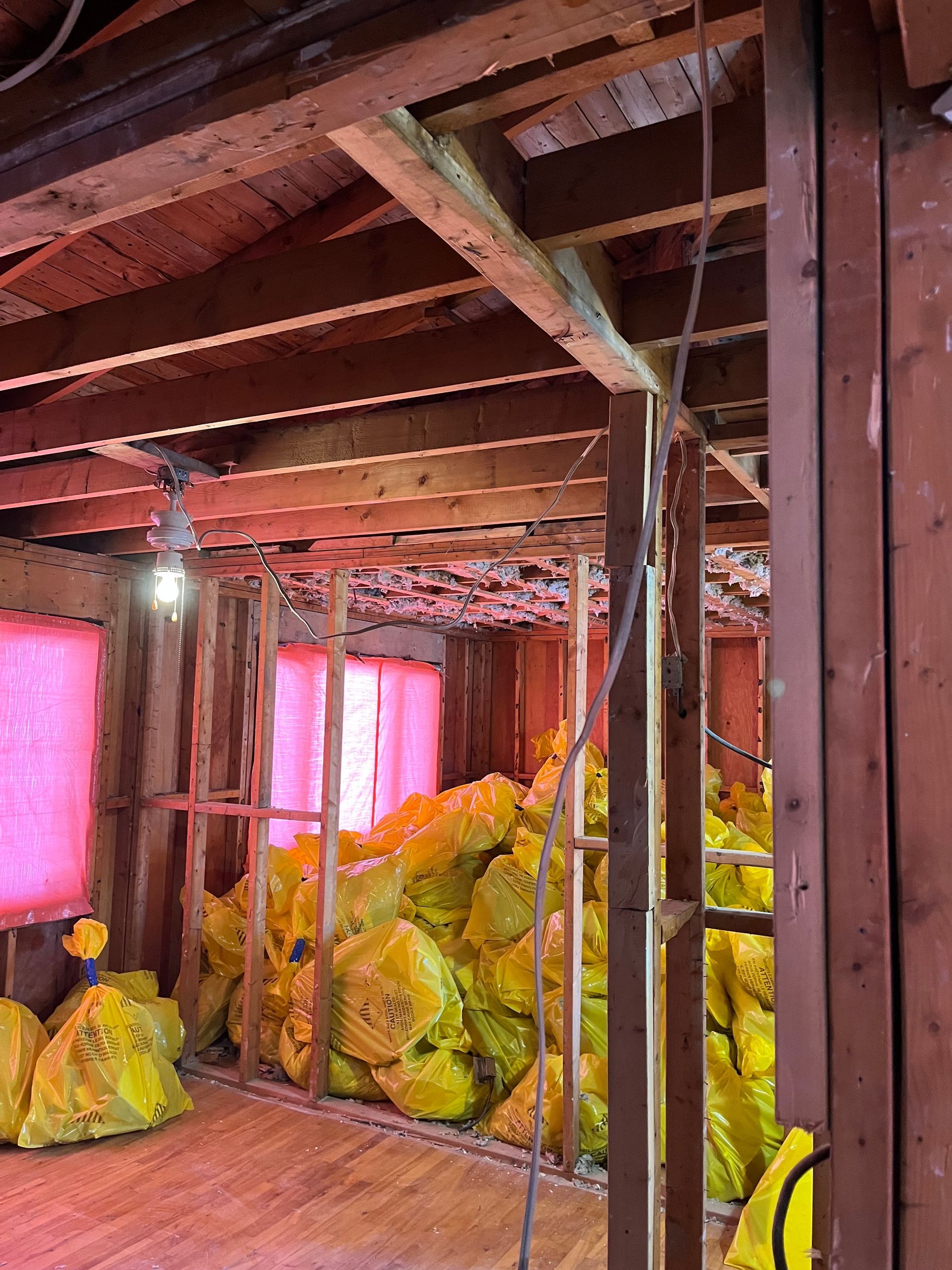 Vue intérieure d'un bâtiment en rénovation. Charpente apparente, isolation en sacs jaunes et câblage apparent.