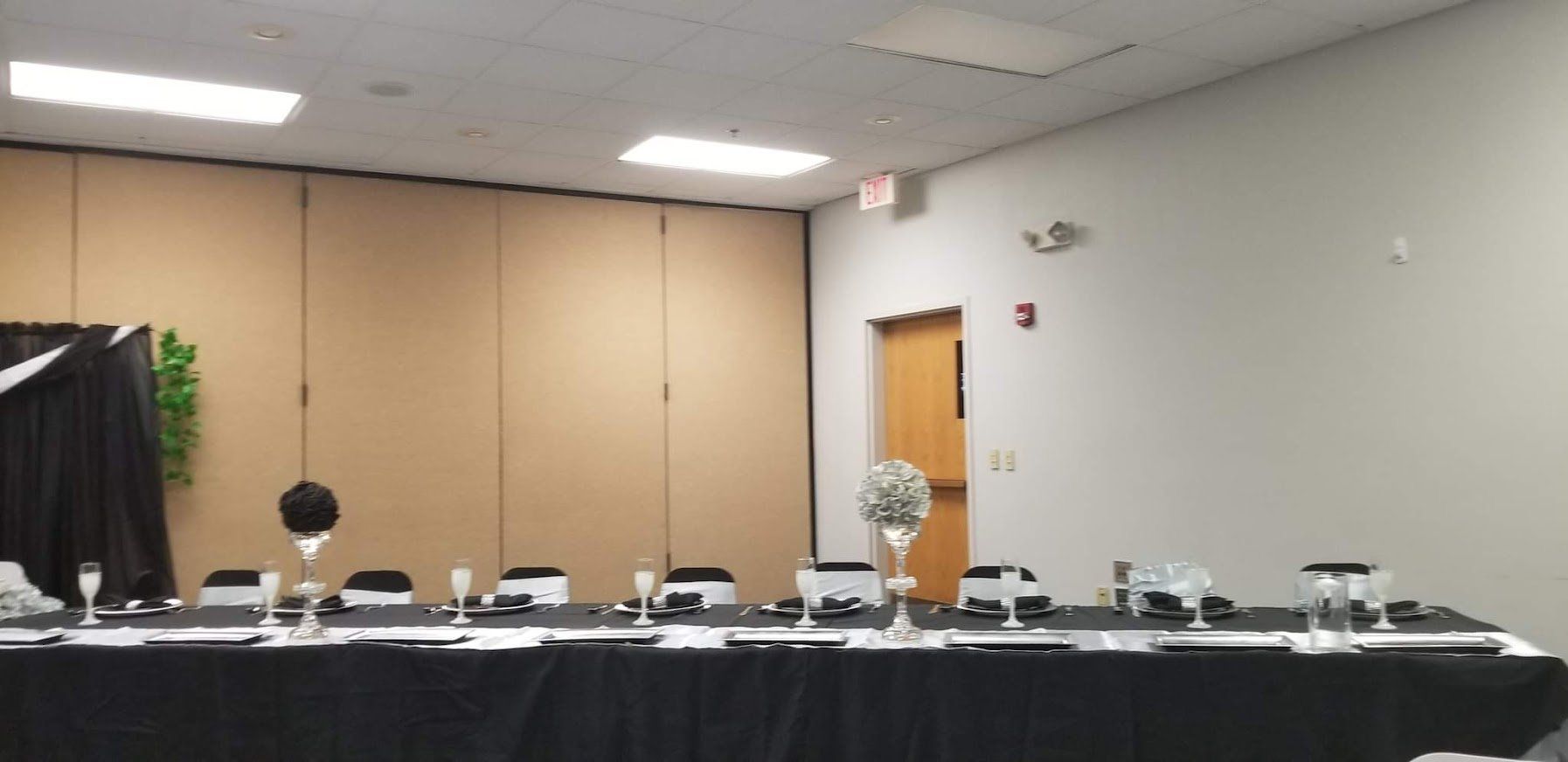 Empty conference room with a long black-draped table and a few items set up against beige walls.