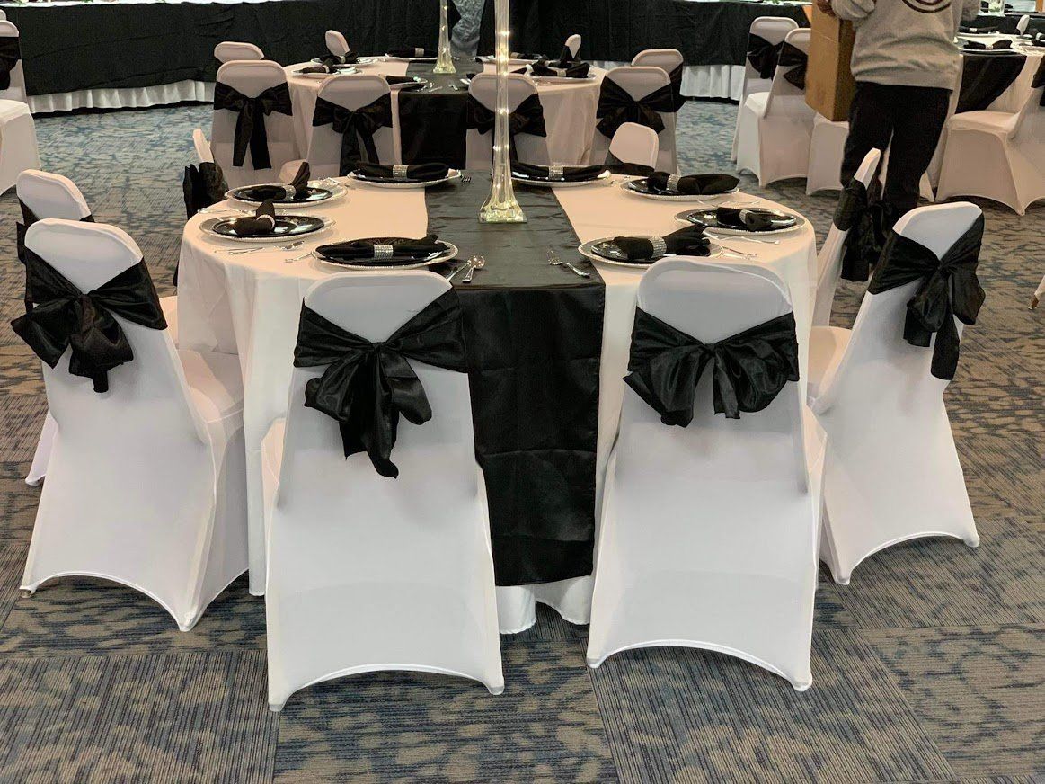 Round banquet table with black-and-white chair covers in a decorated event hall